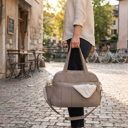 Sac à langer week-end taupe porté à la main dans la rue