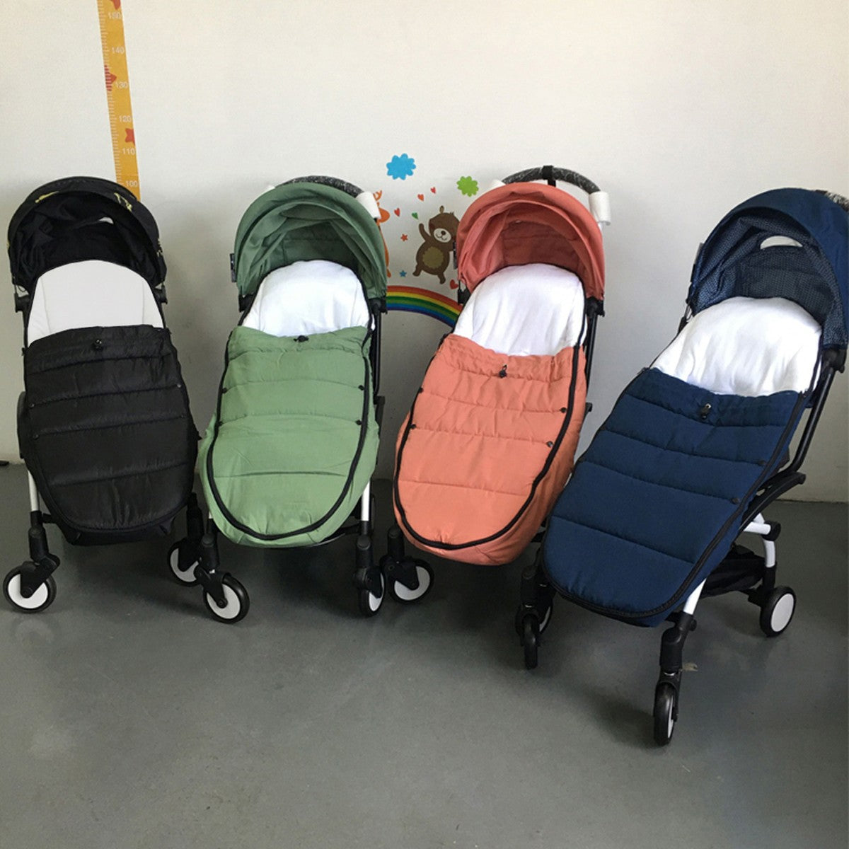 Quatre chancelières installées sur des poussettes compactes : noire, verte, terracotta et bleu marine