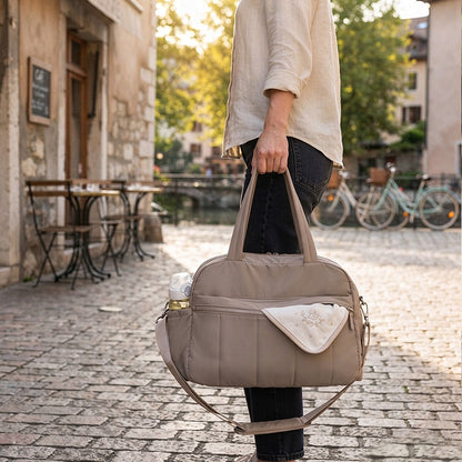 Sac à langer week-end taupe porté à la main dans la rue